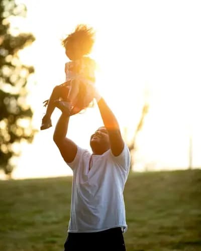 A happy father lifting his daughter up in the air for sunset